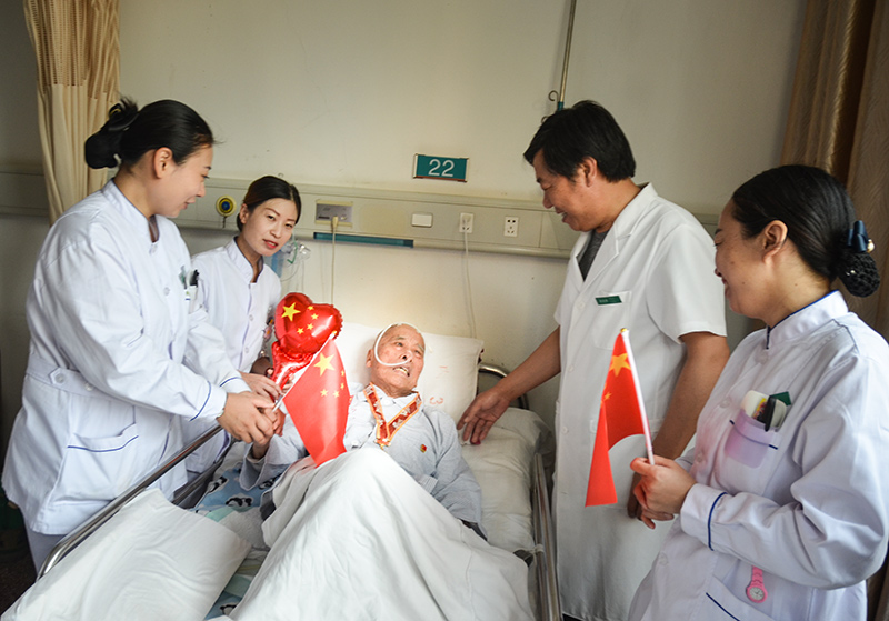 4峰峰總醫院國慶節當日內三科病房里醫護們為93歲的患者秦武平帶上中共中央、國務院中央軍委頒發的國慶70周年紀念章并和他一起歡度國慶，秦爺爺曾參加過南征北戰、孟良崮戰役、淮海戰役、抗美援朝是一名老軍人、老革命 作者：肖建華(2).jpg
